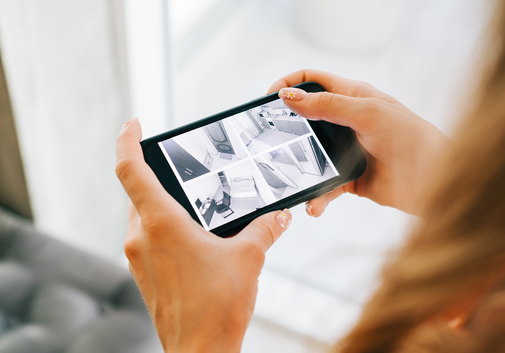 Caucasian woman monitoring security cameras on smartphone indoor